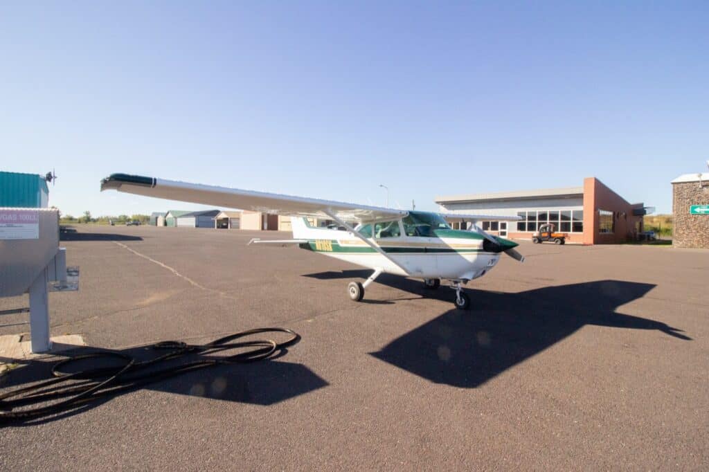 The green-and-white Cessna 172 N616SK parked on the ramp at KSUW with the terminal building behind it.